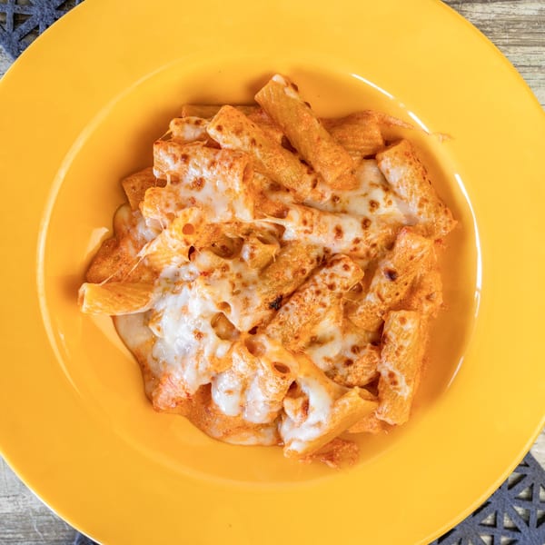 Baked ziti pasta with melted cheese and red sauce in a yellow bowl from Romano's Pizza.